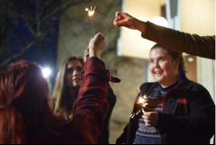 Temple student Jill Caldwell smiles as she looks at one of her peers holding up a sparkler at protest the night before President Donald Trump's inauguration. | THE TEMPLE NEWS